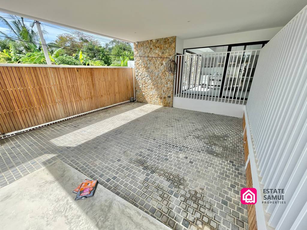 Covered parking area with stone walls and entrance gate