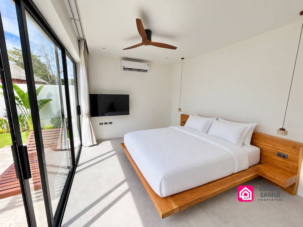 Bright bedroom with wooden bed and glass doors to the garden
