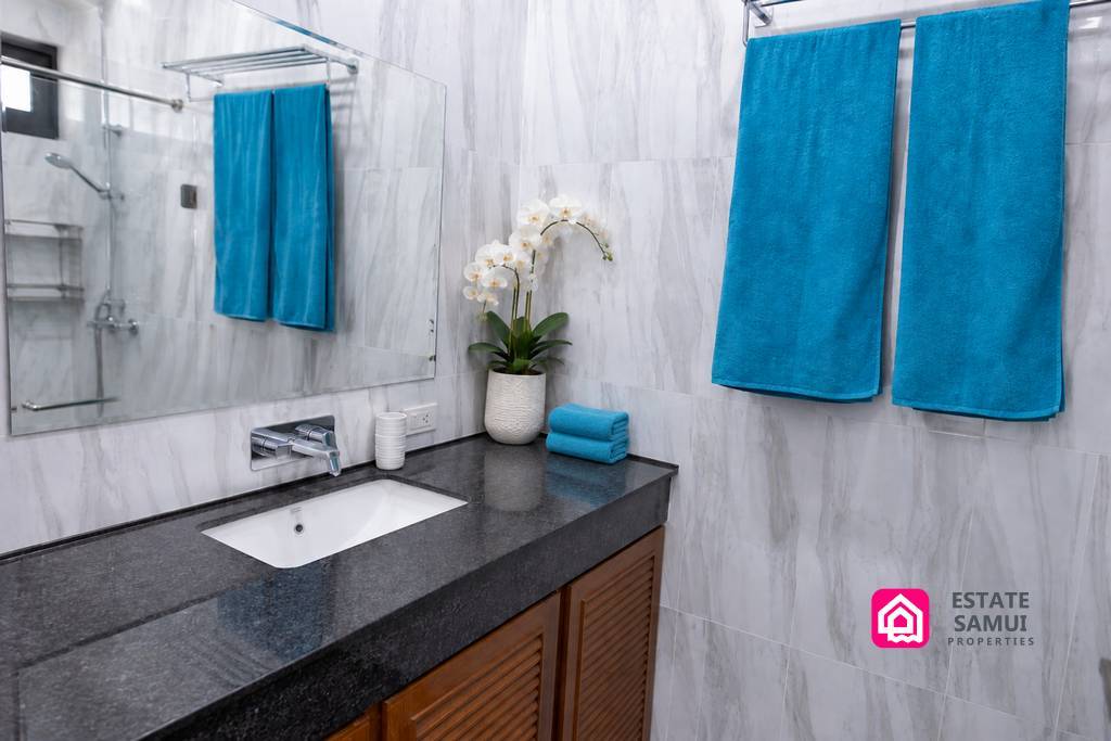 Bathroom vanity with dark stone worktop and turquoise towels