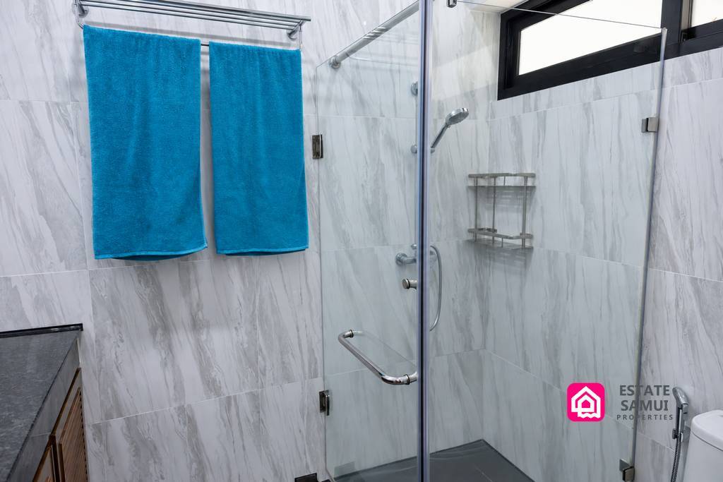 Glass enclosed shower with marble effect tiled walls