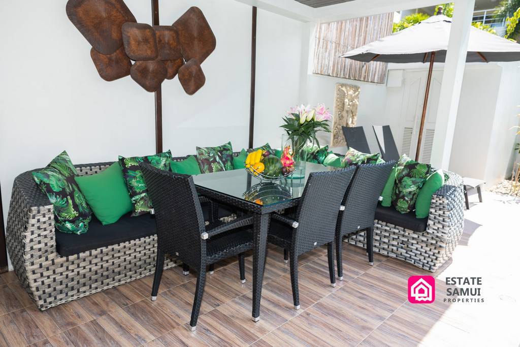 Covered outdoor dining area with rattan seating and tropical cushions