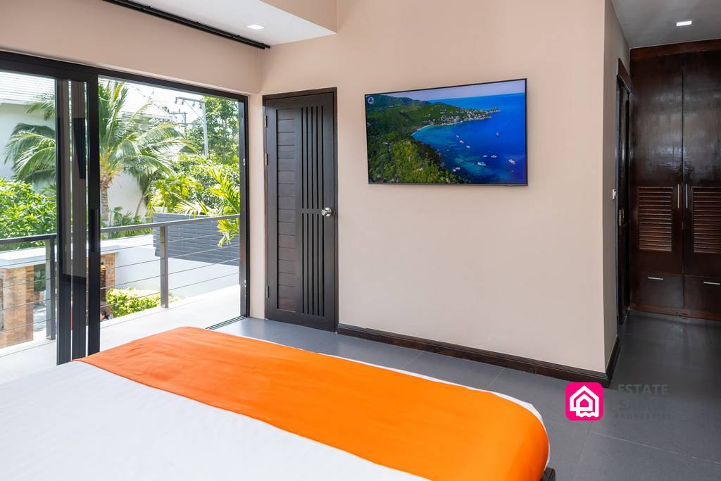 Bedroom with balcony access, television and orange bed runner