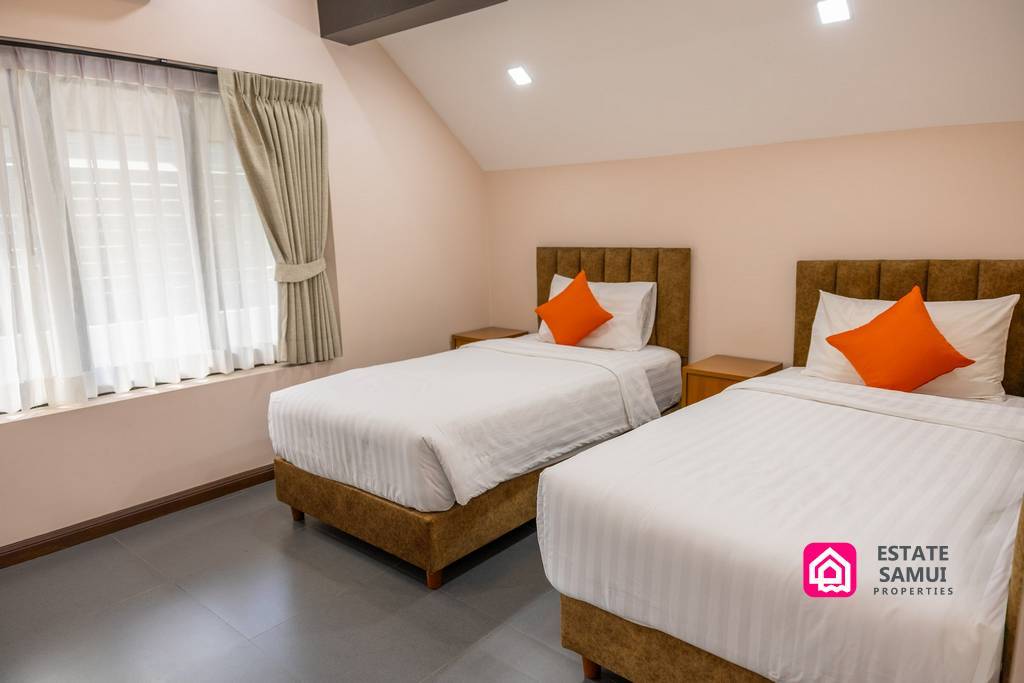 Twin bedroom with two single beds and orange cushions