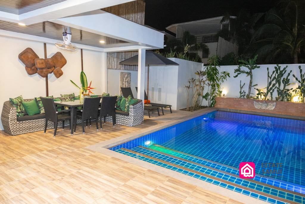 Illuminated swimming pool and covered outdoor dining area at night