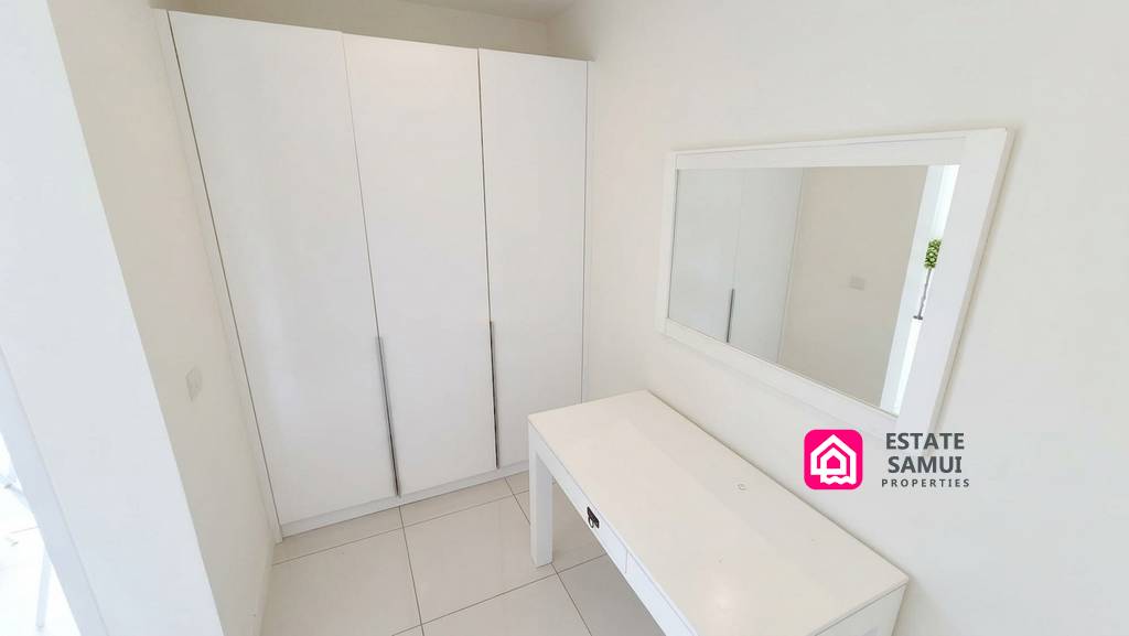 Bright dressing area with fitted wardrobes, vanity and mirror