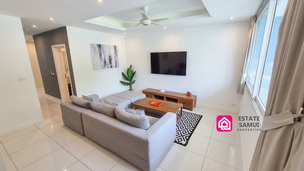 Spacious tiled lounge with wall-mounted television and ceiling fan
