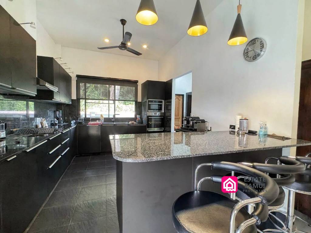 Fully equipped black kitchen with granite breakfast bar and stools