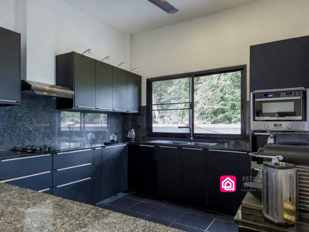 Fitted kitchen with black cabinetry, oven and garden-facing window