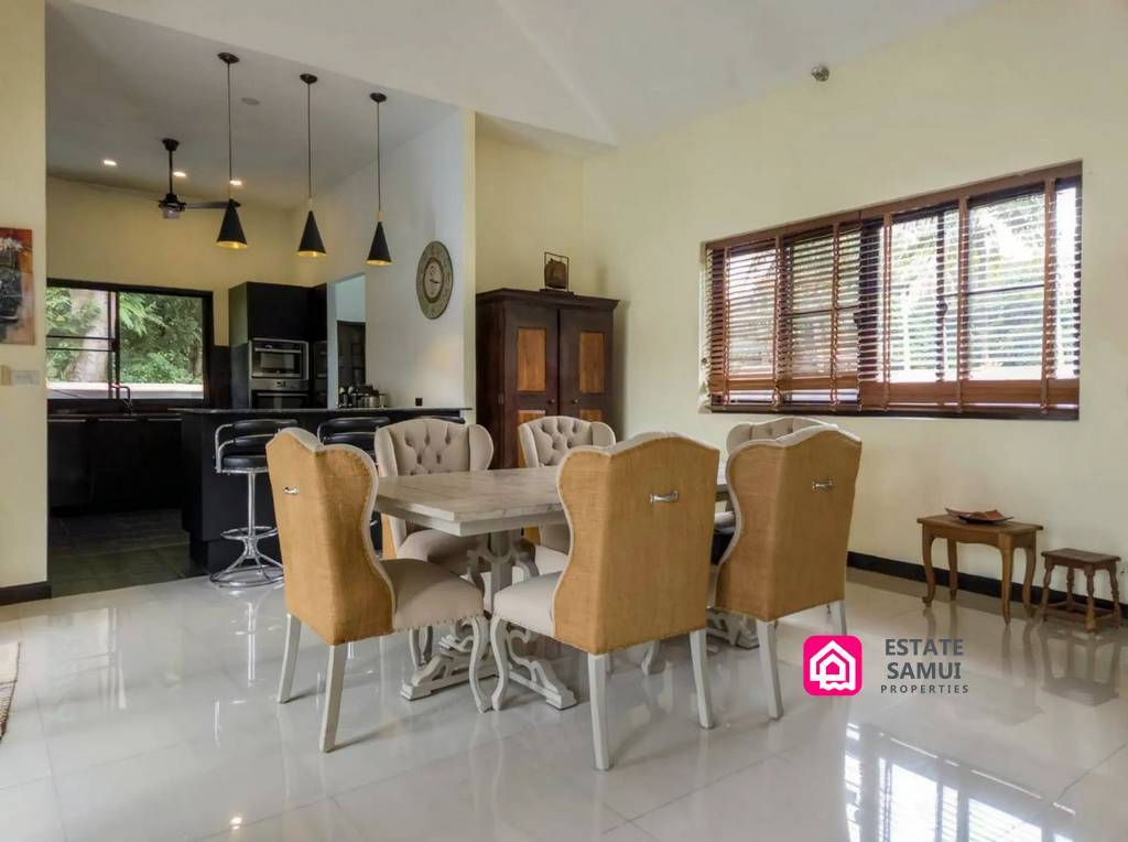 Dining area beside a black fitted kitchen with breakfast bar