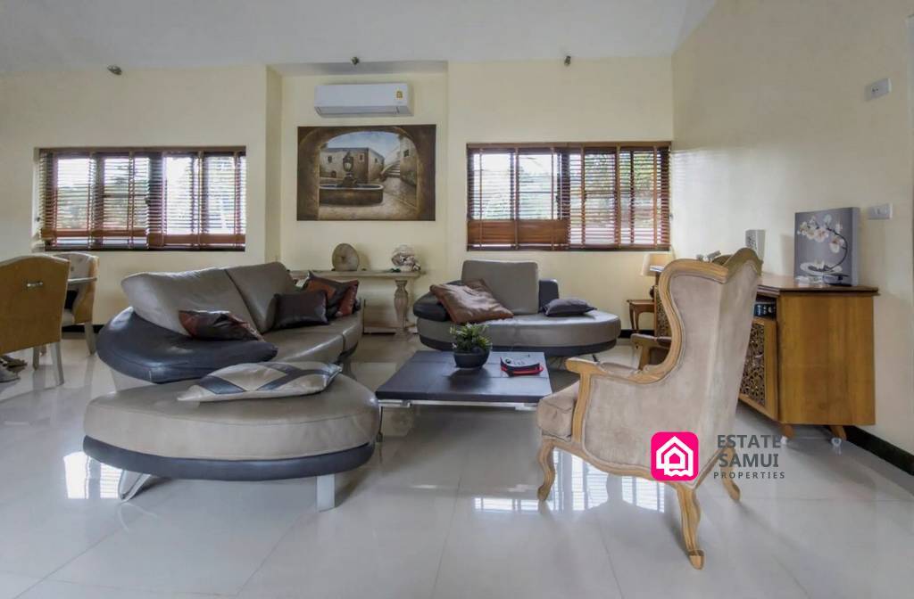 Bright lounge furnished with curved sofas and wooden blinds