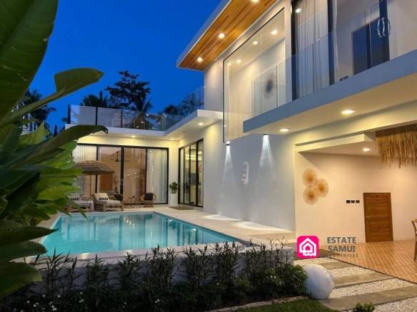 Illuminated villa exterior and swimming pool at dusk