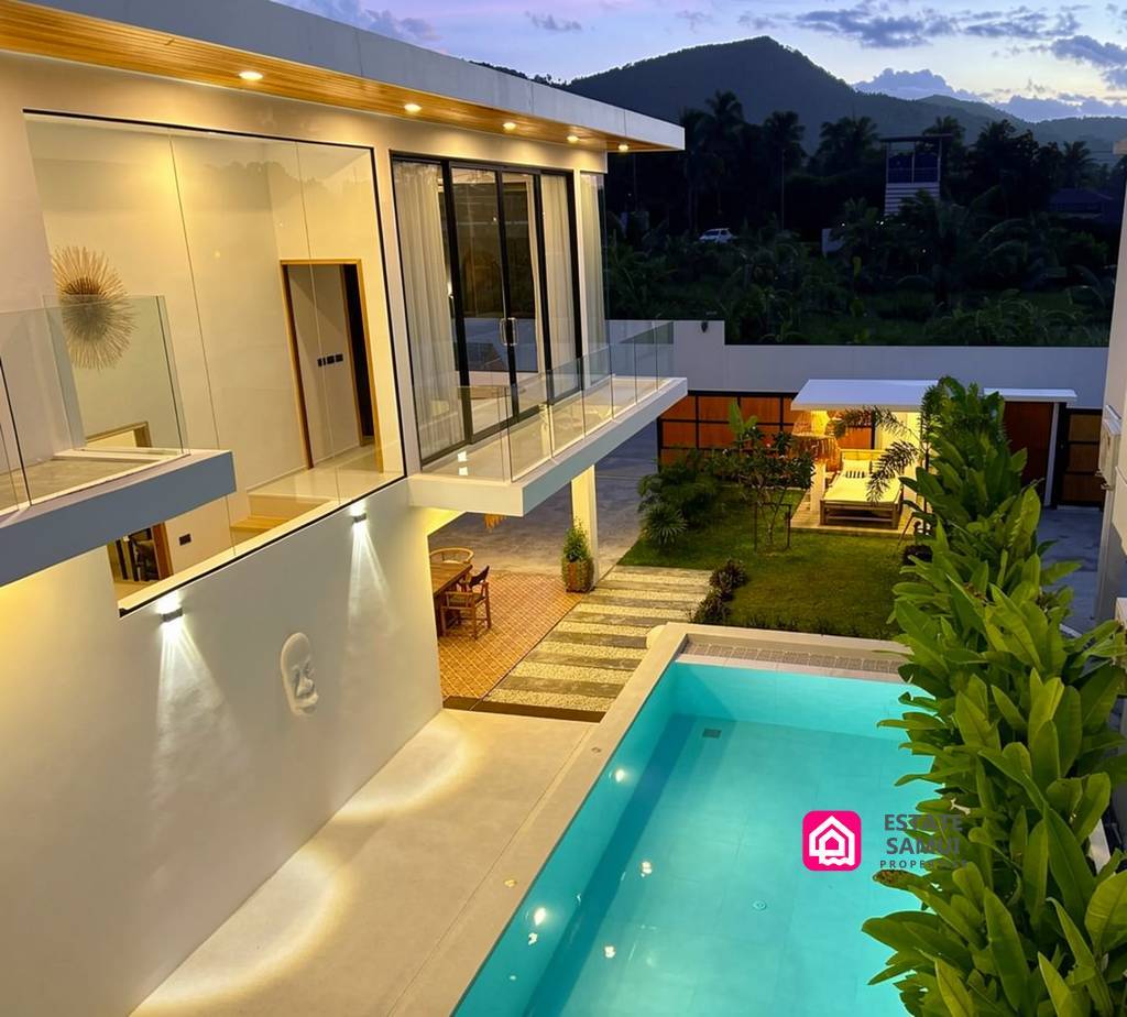 Two-storey villa overlooking the illuminated pool at dusk