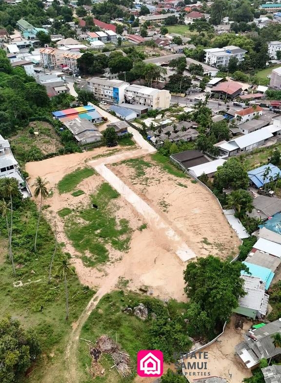 Aerial view of spacious Chaweng land for sale with internal road and surrounding buildings.
