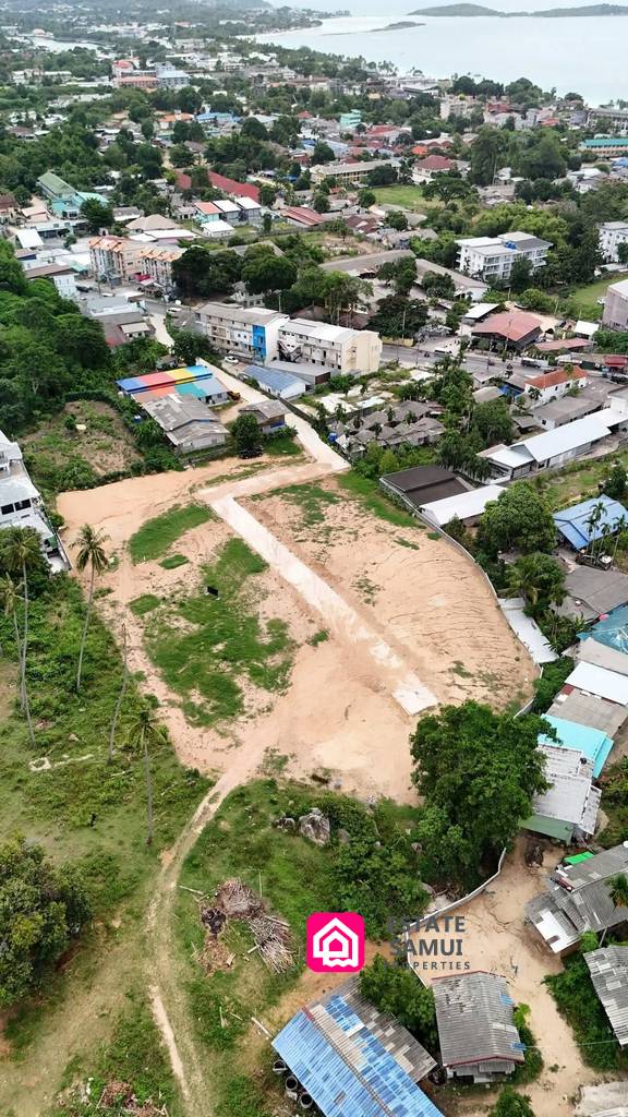 Aerial view of spacious Chaweng land for sale with internal road and surrounding buildings.