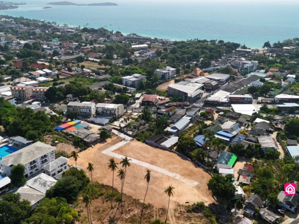 Cleared subdivision with concrete access road, surrounding neighbourhood and coastline beyond.