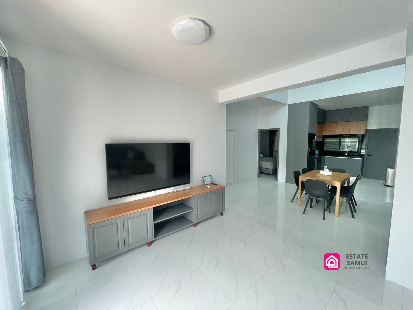 Open-plan living and dining area with television and compact kitchen beyond.