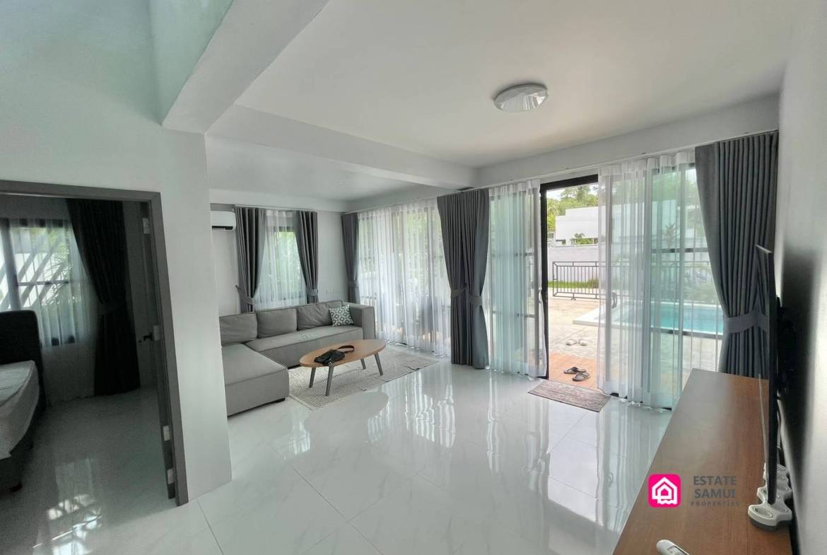 Light-filled lounge with corner sofa and sliding doors opening towards the pool.