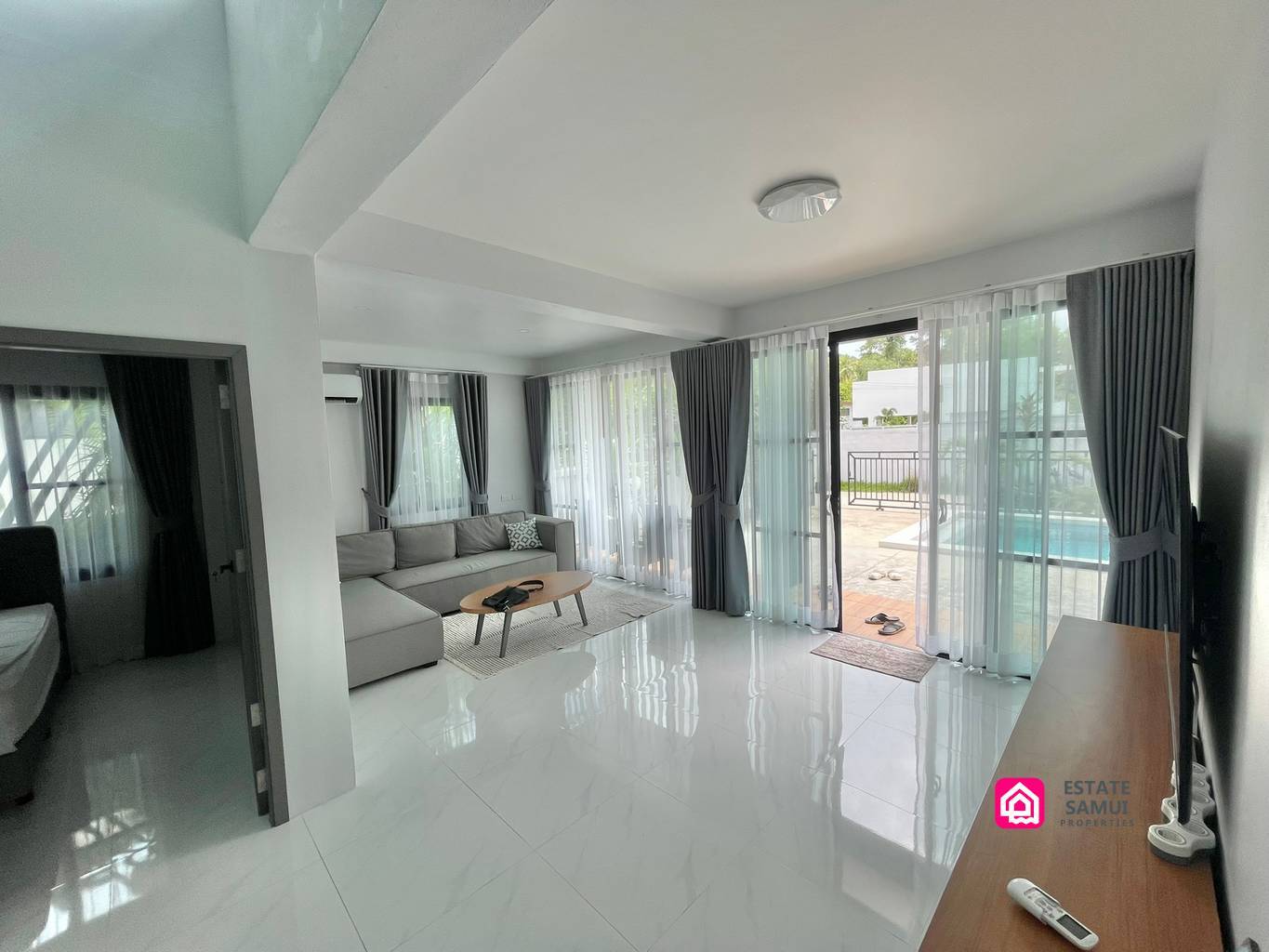 Light-filled lounge with corner sofa and sliding doors opening towards the pool.