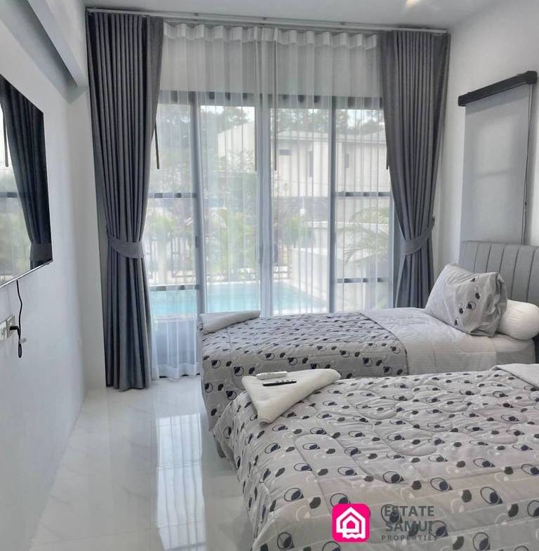 Twin bedroom with wall-mounted television and sliding doors overlooking the pool.