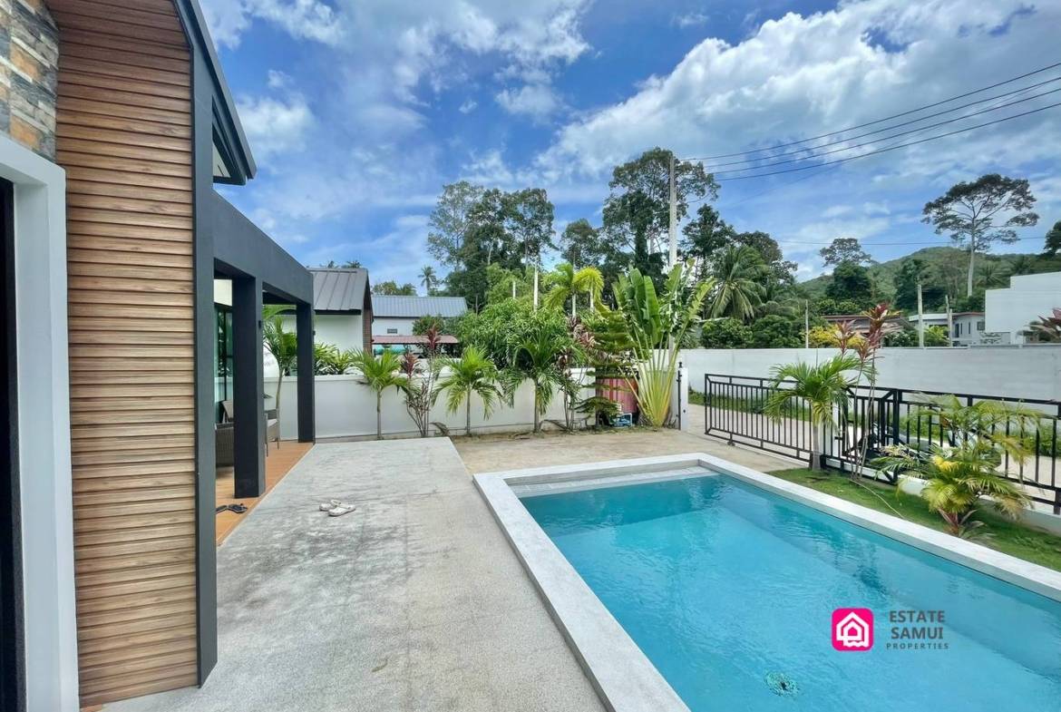 Private pool beside the villa’s terrace, with gated entrance and greenery.
