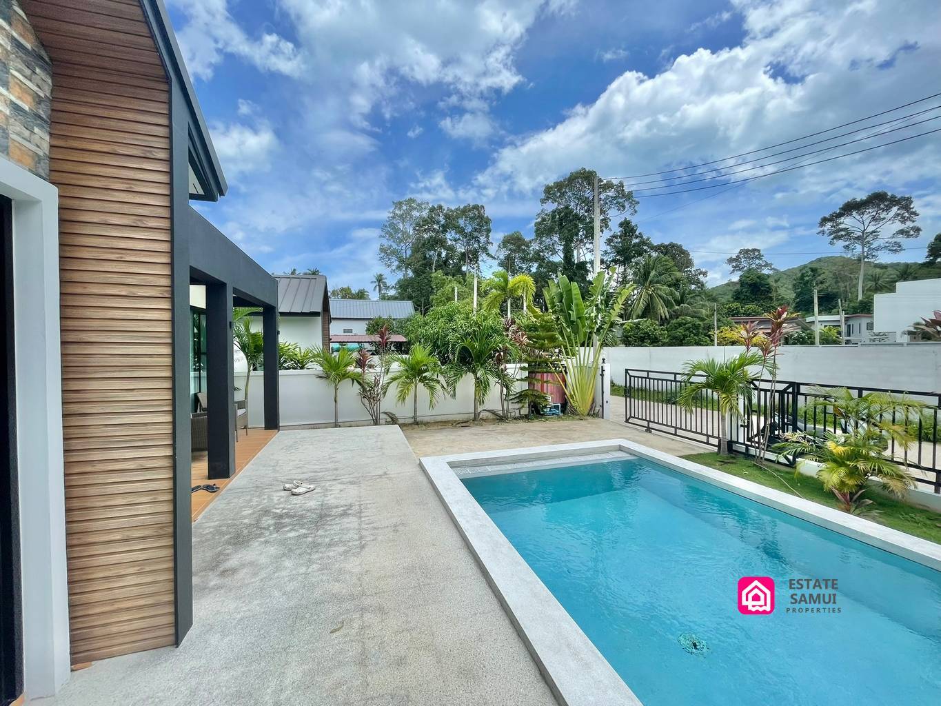 Private pool beside the villa’s terrace, with gated entrance and greenery.