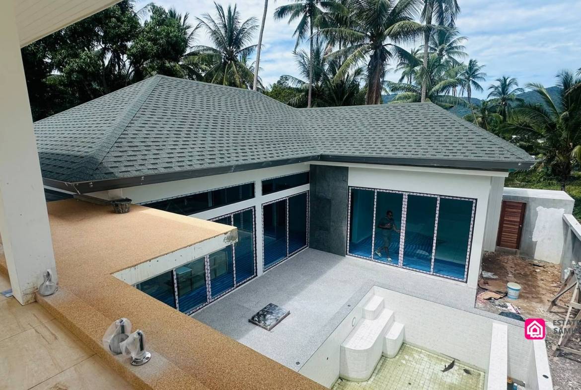 Elevated view of Maenam villa construction with tiled pool and surrounding coconut palms.