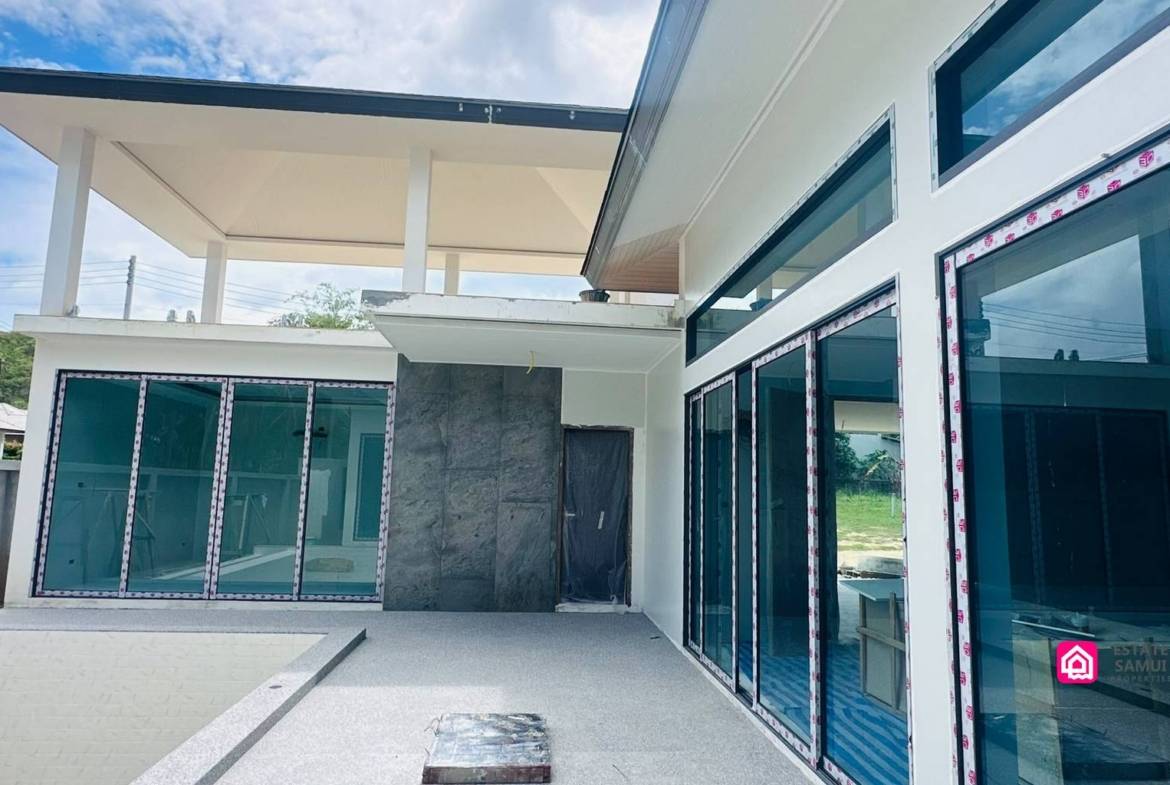 Poolside terrace under construction beside large sliding glass doors.