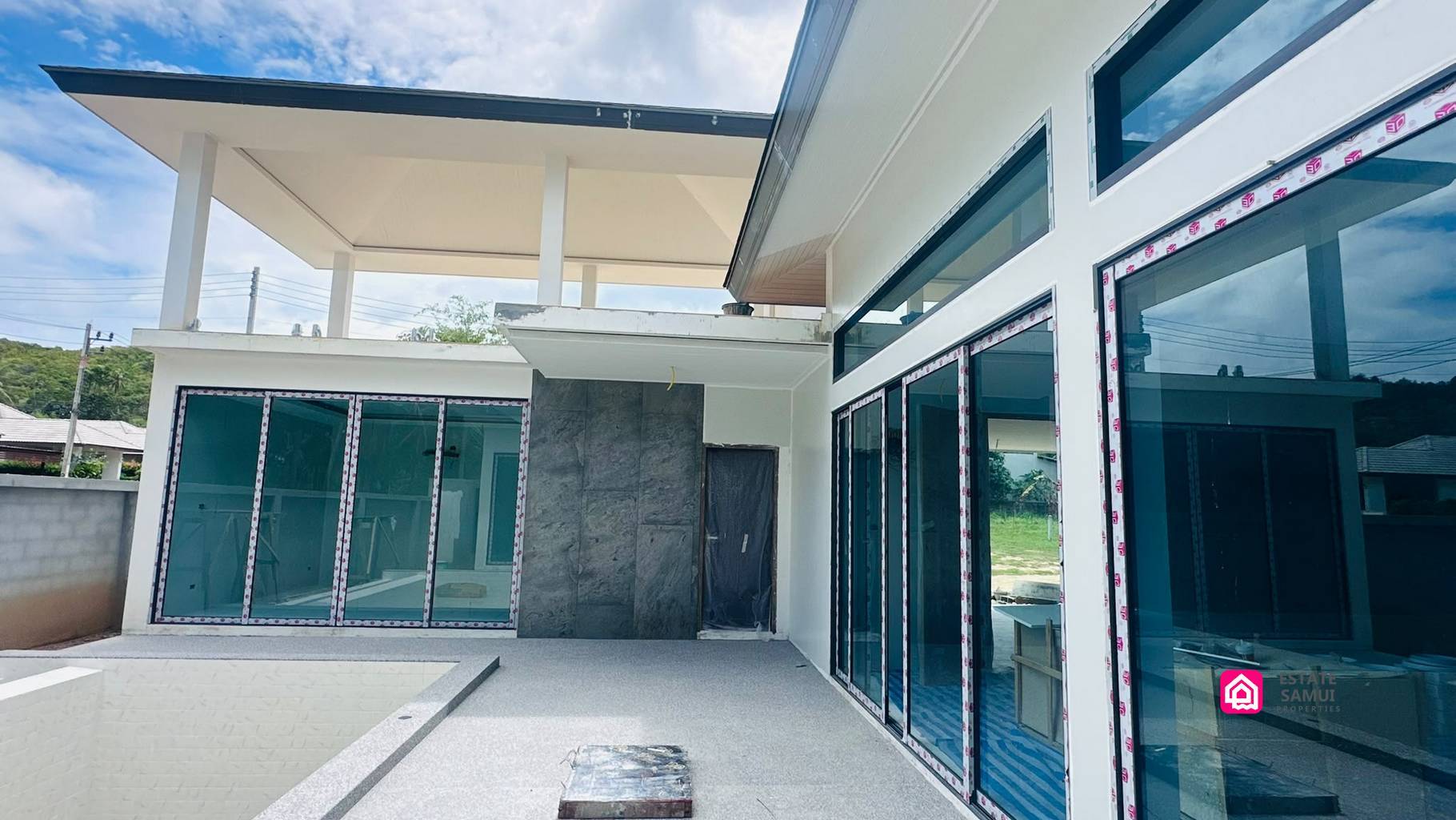 Poolside terrace under construction beside large sliding glass doors.