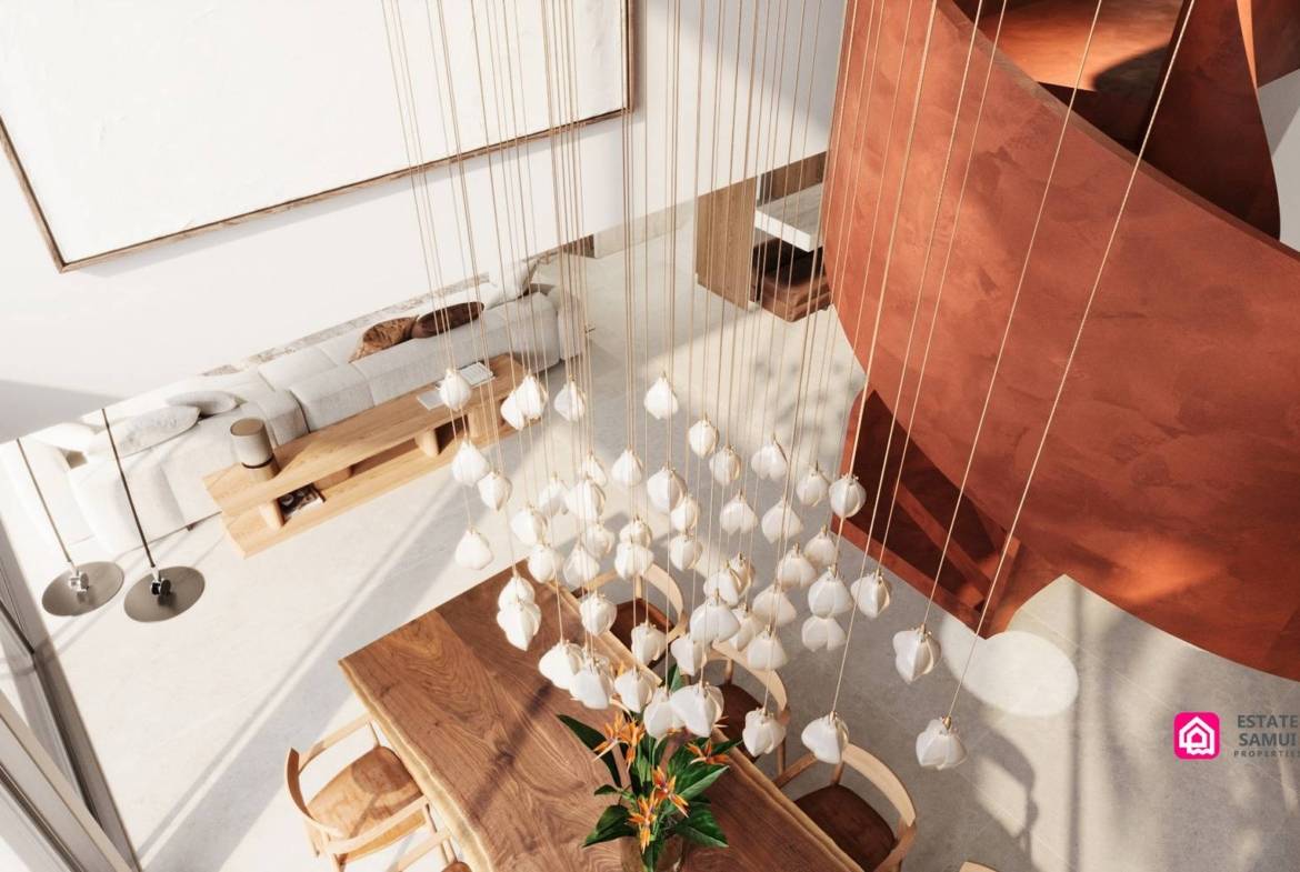 Pendant chandelier above wooden dining table beside curved red staircase.